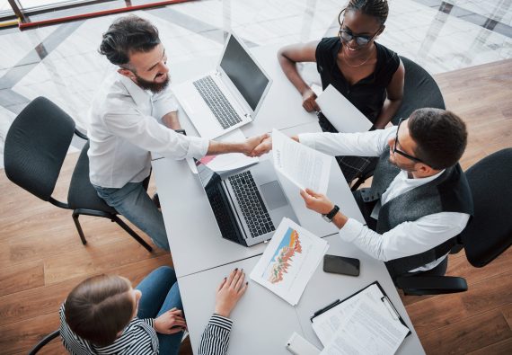 Young employees sitting in the office at the table and using a laptop, a team work brainstorming meeting concept. Young employees sitting in the office at the table and using a laptop, a team work brainstorming meeting concept